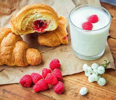 freshly baked cornetto, a glass of milk and berries